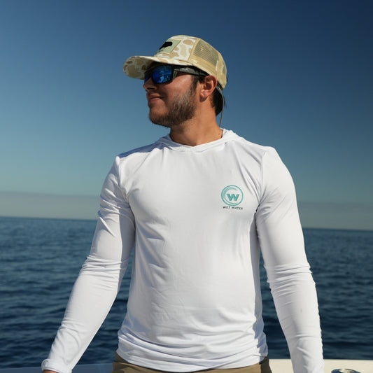 Man on a boat wearing the white Wet Water Bluefin Performance Hoodie — front view on the water