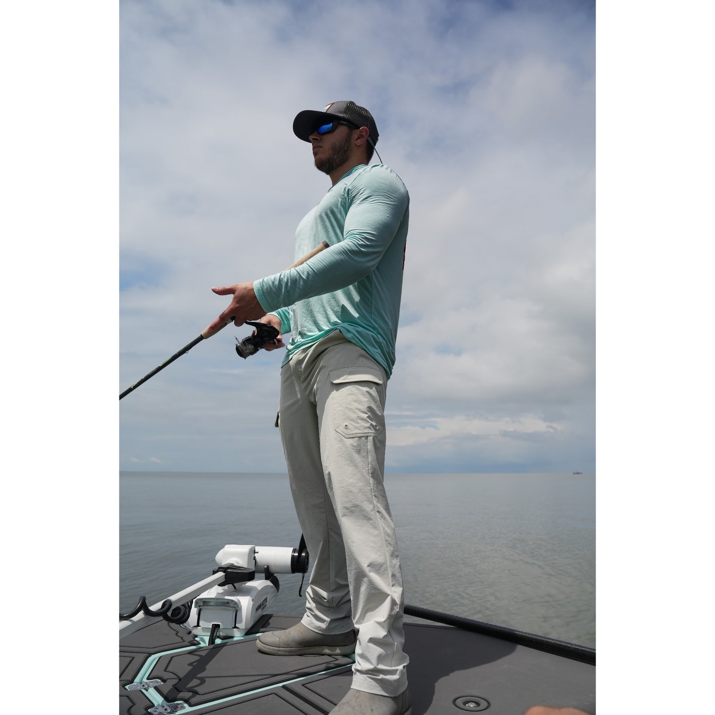 Angler on a boat holding a rod, wearing the Wet Water Coastal Bamboo Hoodie