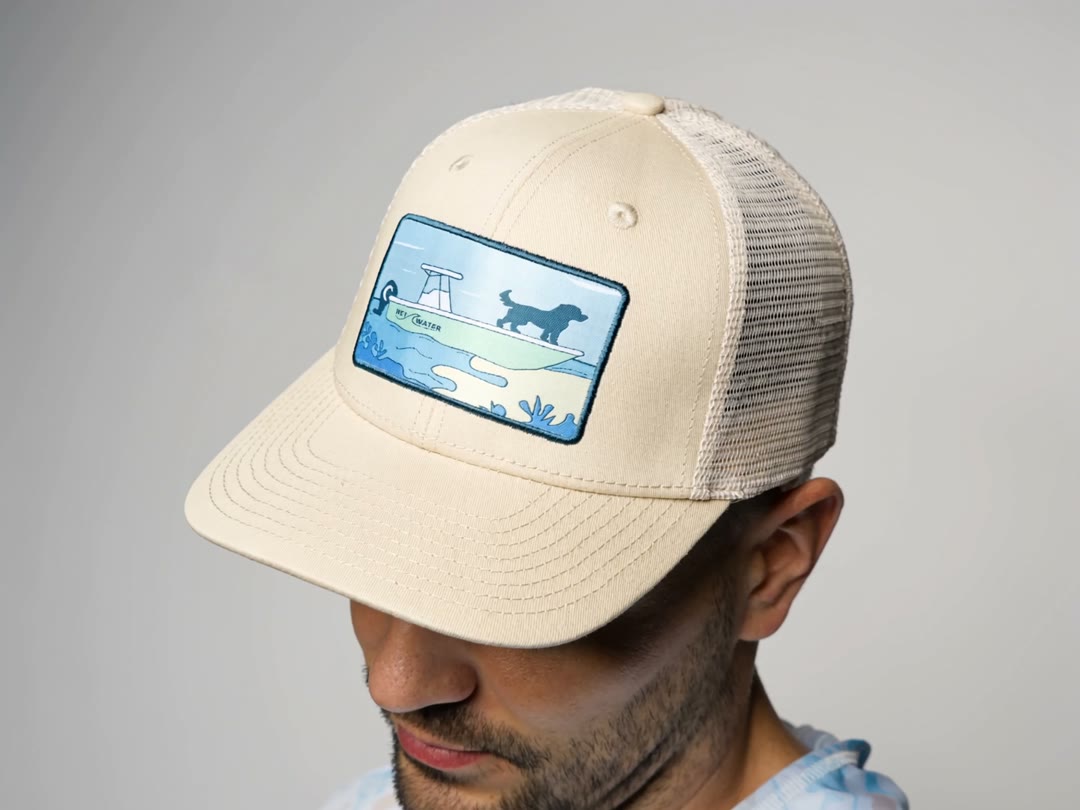 Model wearing the Wet Water Man's Best Friend hat in tan, showing the dog patch — side view